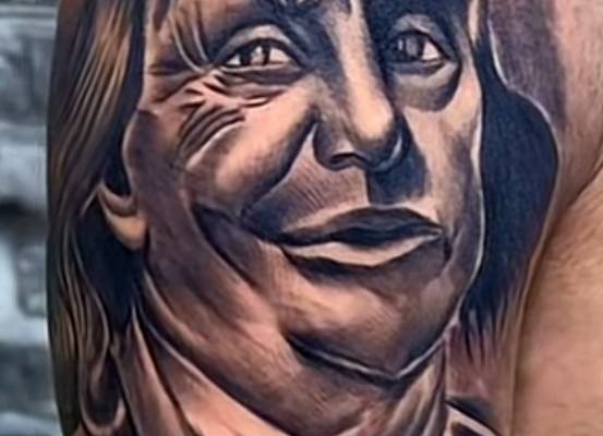 Ritratto tatuato in nero e grigio sulla parte alta del braccio