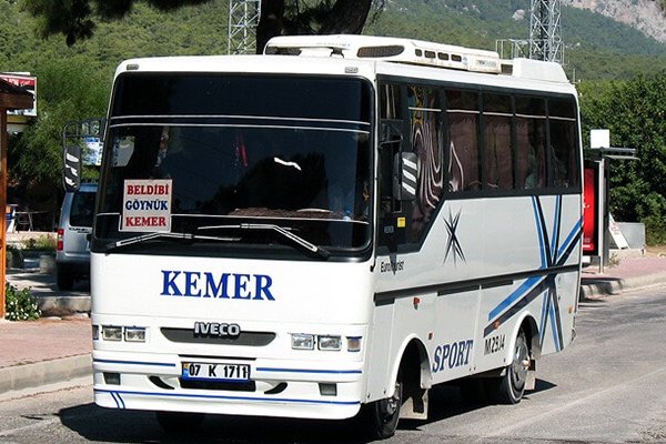 White bus displaying Kemer, with mountains in the background.