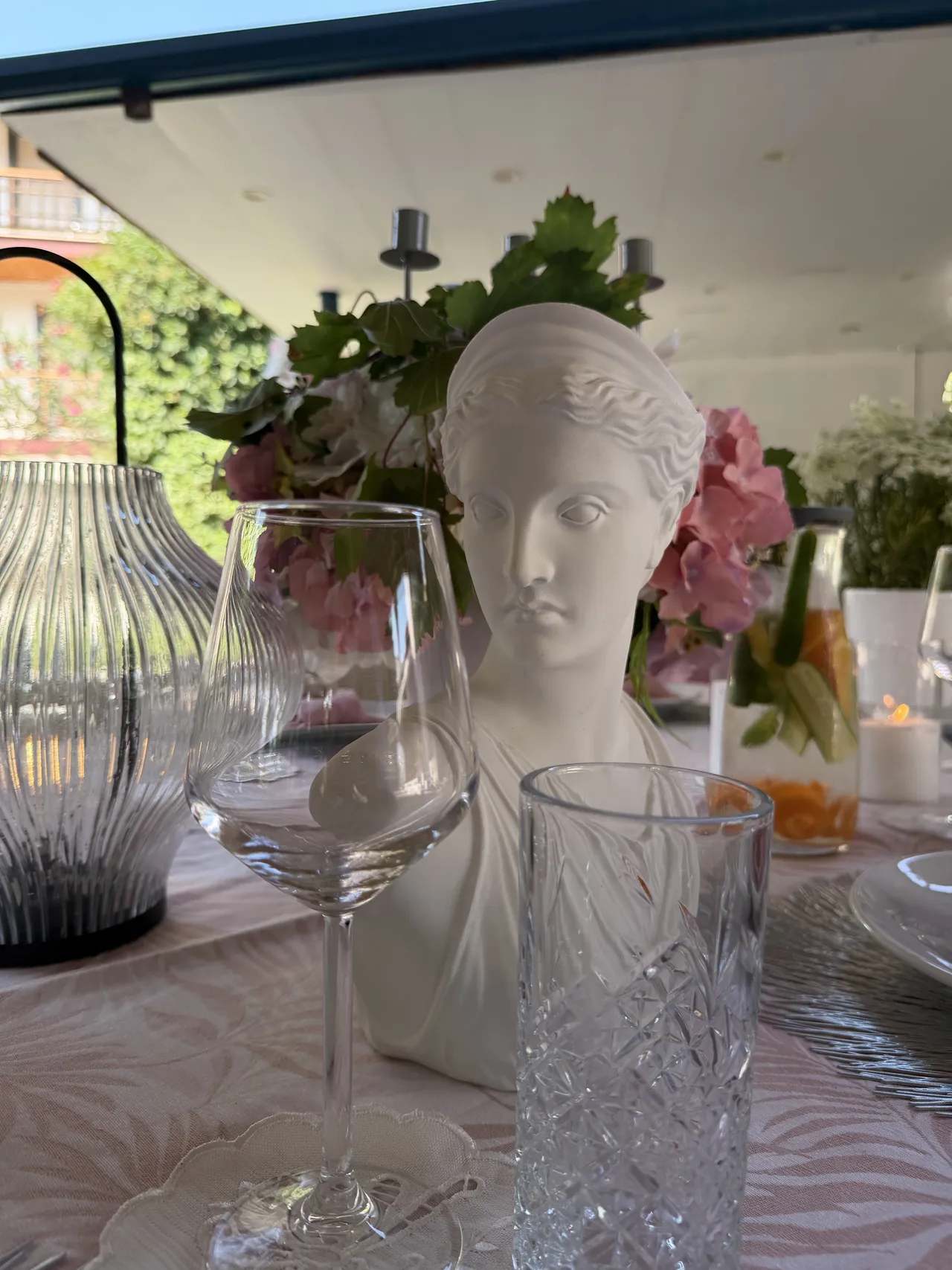 Flowers and a decorative bust among the glasses on the celebration table.
