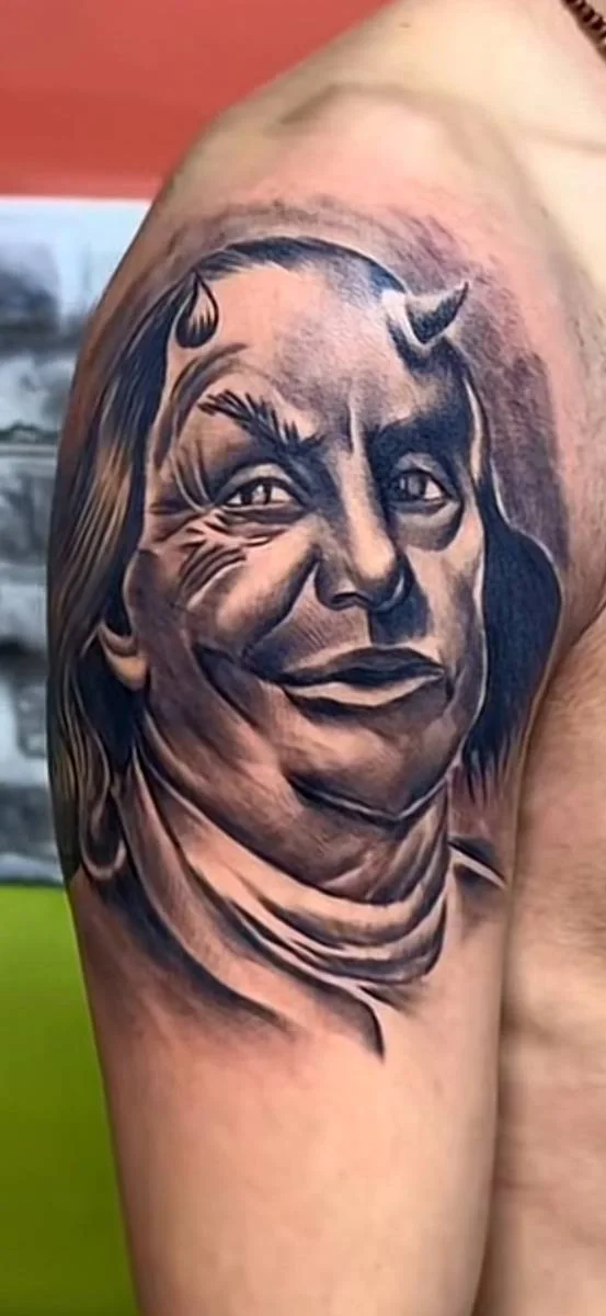 Ritratto tatuato in nero e grigio sulla parte alta del braccio